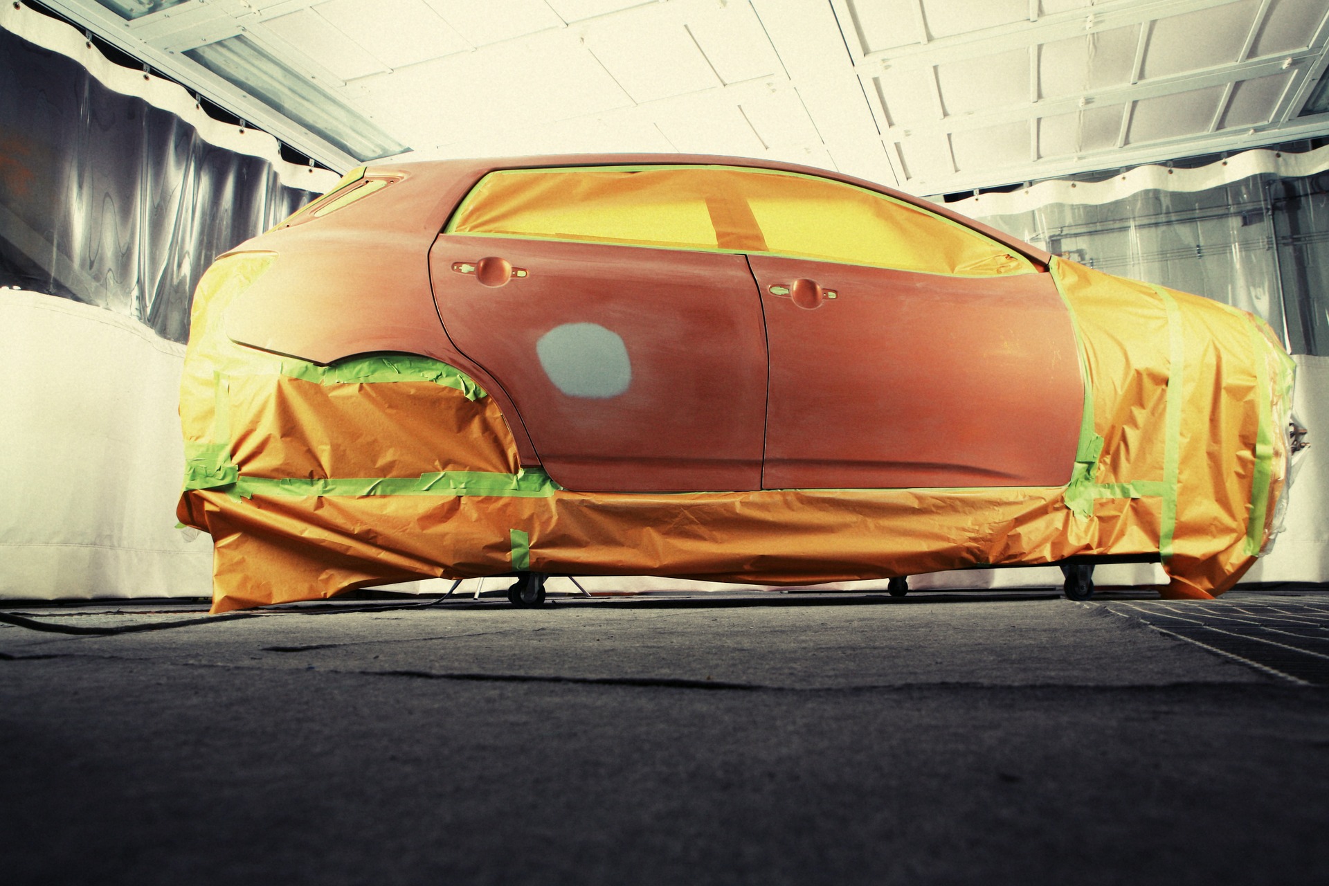 small car taped with brown paper prepping to be spray painted 